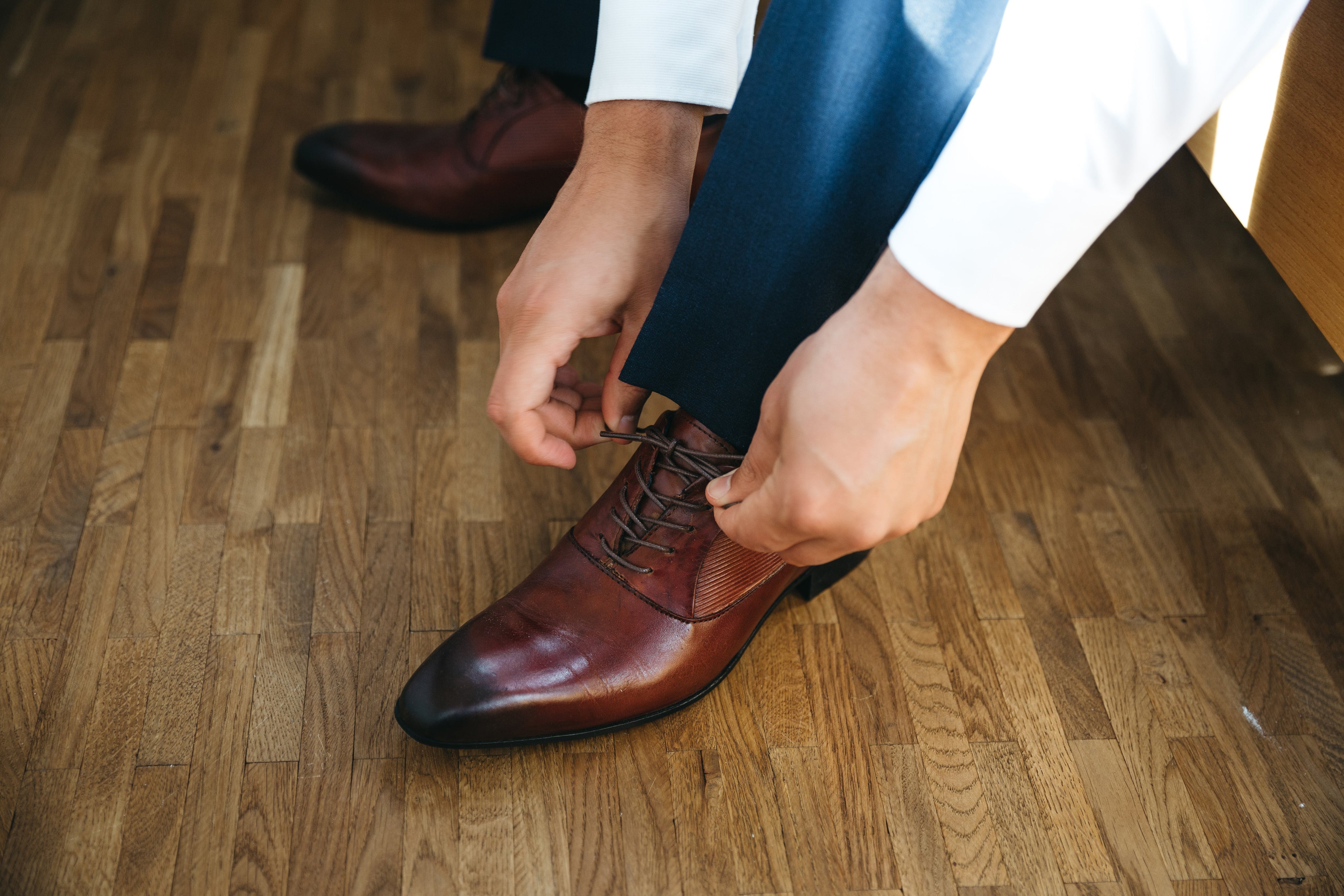 Persona atando los cordones de sus zapatos de cuero