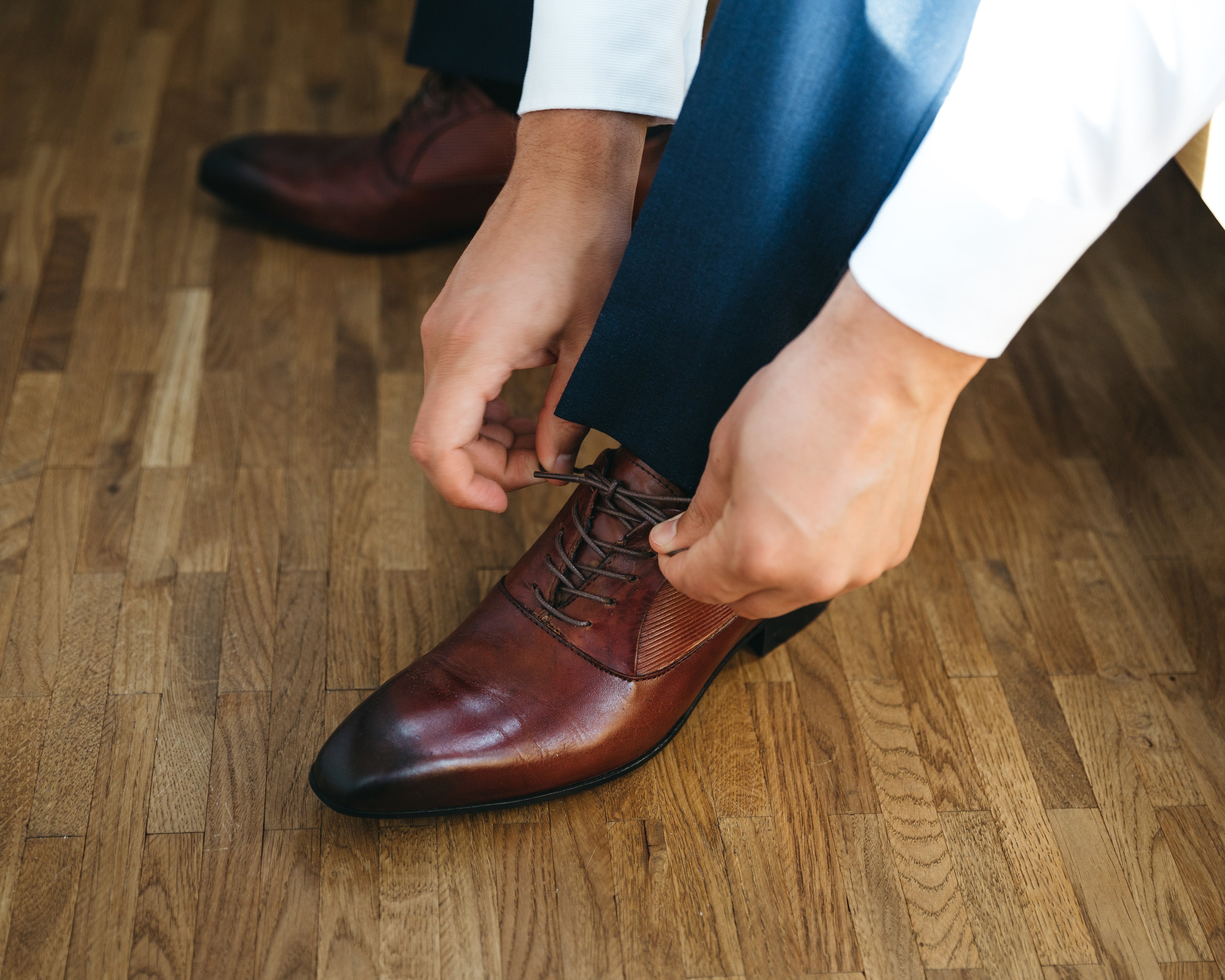 Persona atando los cordones de sus zapatos de cuero